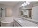 Luxurious bathroom features a soaking tub, granite counters, and a bright vanity mirror at 5902 Sw 112Th Place Rd, Ocala, FL 34476