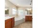 Bathroom with double sinks, vanity, soaking tub, and neutral tile flooring at 6279 Se 8Th Lane, Ocala, FL 34472