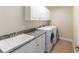 Bright laundry room featuring a utility sink, washer, dryer, storage cabinets, and tile floors at 6279 Se 8Th Lane, Ocala, FL 34472