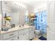 Well-lit bathroom with white cabinetry, double sink, and coastal-themed shower curtain at 6450 Sw 83Rd Ln, Ocala, FL 34476