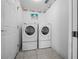 Efficient laundry area with a stacked washer and dryer set against white walls and tiled flooring at 7178 Sw 113Th Loop, Ocala, FL 34476
