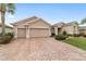 Attractive home featuring a paver driveway leading to a spacious two-car garage, complemented by lush landscaping at 9863 Sw 63Rd Loop, Ocala, FL 34481