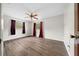 Spacious bedroom with wood flooring, ceiling fan, and two windows with burgundy curtains at 4040 E Fort King St, Ocala, FL 34470