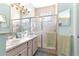 Bright bathroom featuring double sinks, tiled shower with glass door, and modern fixtures at 10055 Sw 90Th Loop, Ocala, FL 34481