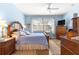 Comfortable main bedroom boasts a spacious layout, ceiling fan, and a large window at 10055 Sw 90Th Loop, Ocala, FL 34481