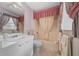 Vintage bathroom featuring a tub with shower and vanity with decorative wallpaper, plus pink accents at 1019 Avalon Ave, Lady Lake, FL 32159