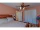 Peach colored bedroom featuring wood frame bed, ceiling fan, and closet at 10376 Se 43Rd Ct, Belleview, FL 34420