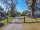 View of the gated entry to the home's drive, featuring mature trees at 10376 Se 43Rd Ct, Belleview, FL 34420