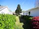 Landscaped yard with green lawn and mature shrubs between two homes under a clear, blue sky at 11552 Sw 138Th Ln, Dunnellon, FL 34432