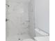 Bright bathroom features a tiled shower with glass shelves and white flooring at 13292 Sw 112Th Pl, Dunnellon, FL 34432