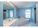 A luxurious bathroom with a soaking tub, a double window, and a marble countertop sink at 13677 Sw 40Th Avenue Rd, Ocala, FL 34473