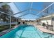 Beautiful screened-in pool features a tile border, a white picket fence, chairs, and greenery at 13677 Sw 40Th Avenue Rd, Ocala, FL 34473