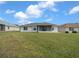 Back of a white home with a screened-in lanai and a green lawn under a blue sky at 17799 Se 125Th Cir, Summerfield, FL 34491