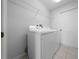 Bright laundry room featuring a modern washer and dryer set, tile flooring, and convenient overhead shelving at 17799 Se 125Th Cir, Summerfield, FL 34491