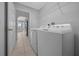 Bright laundry room featuring a modern washer and dryer set, tile flooring, and convenient overhead shelving at 17799 Se 125Th Cir, Summerfield, FL 34491