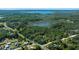 Expansive aerial view of a wooded lot with a lake in the distance under a clear, sunny sky at 18434 Se 24Th St, Silver Springs, FL 34488