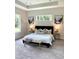 Bright main bedroom featuring tray ceiling, neutral decor, large windows, carpet, and stylish furniture at 1929 Nw 85Th Loop, Ocala, FL 34475