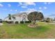 Exterior view of a home with a manicured lawn and mature landscaping featuring palm trees at 2399 Nw 53Rd Avenue Rd, Ocala, FL 34482