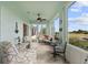 Bright sunroom featuring tile floors, ceiling fan, sitting area, and views of the lush green golf course at 2399 Nw 53Rd Avenue Rd, Ocala, FL 34482