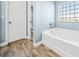Bathroom featuring a separate soaking tub, wood floors, and large format tile at 6875 Se 11Th Pl, Ocala, FL 34472