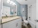 Bright bathroom featuring a granite countertop, white cabinets, tub with tile surround and blue accent wall at 6875 Se 11Th Pl, Ocala, FL 34472