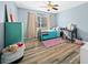 Bedroom featuring wood floors, a ceiling fan, a turquoise accent wall, and large window for natural light at 6875 Se 11Th Pl, Ocala, FL 34472