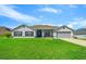 Charming one-story home with lush green lawn and a blue front door with a gray exterior and two car garage at 6875 Se 11Th Pl, Ocala, FL 34472