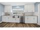 Modern kitchen with stainless steel appliances, wood-look floors, and sleek white cabinets at 6875 Se 11Th Pl, Ocala, FL 34472