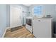 Bright laundry room with modern washer and dryer set, wood-look flooring, and exterior access door at 6875 Se 11Th Pl, Ocala, FL 34472