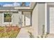 Inviting front entrance featuring a white door, textured gray exterior, and manicured landscaping at 7772 Sw 146Th Lane Rd, Ocala, FL 34473
