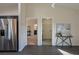Hallway with a view of the bathroom and laundry room with stainless steel refrigerator, table and wall art at 7772 Sw 146Th Lane Rd, Ocala, FL 34473