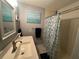 Bathroom featuring a shower and tub combo with seashell themed shower curtain, art, and decor at 1008 Se 26Th St, Ocala, FL 34471