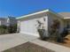 Garage featuring a modern door, manicured landscaping, and a concrete driveway at 13100 Se 93Rd Terrace Rd, Summerfield, FL 34491