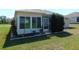 Sunroom exterior featuring glass windows, a door, and manicured landscaping at 13100 Se 93Rd Terrace Rd, Summerfield, FL 34491