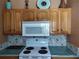 This kitchen features wood cabinets, a white microwave, and a white stove top with decorative backsplash at 1546 Sw 153Rd Sw Ct, Ocala, FL 34481