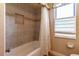 Bathtub with shower featuring tiled walls, built-in shelf, and a window for natural light at 16276 Sw 14Th Ct, Ocala, FL 34473