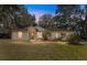 Charming single-story home with a well-manicured lawn and mature trees at dusk at 17153 Se 79Th Street Rd, Ocklawaha, FL 32179