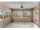 A sunroom with tile flooring, ceiling fan, and windows to view the surrounding trees at 17153 Se 79Th Street Rd, Ocklawaha, FL 32179