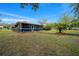 Home's outdoor screened porch with blue accents complemented by an expansive lawn and thoughtful landscaping at 1905 Nw 25Th Ave, Ocala, FL 34475