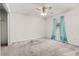 Spacious carpeted bedroom featuring a ceiling fan and a window with blue curtains at 21 Pecan Pass Ter, Ocala, FL 34472