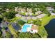 Aerial view of a community featuring a pool, tennis court, lake and well-maintained homes with lush greenery at 2418 Se 17Th Cir, Ocala, FL 34471