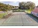 Outdoor community tennis court with green surface, benches and perimeter fence surrounded by trees and landscaping at 2418 Se 17Th Cir, Ocala, FL 34471