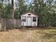 Exterior view of a small, white home with red trim and mature trees at 3081 Ne 49Th St, Ocala, FL 34479