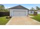 Attached two-car garage with modern gray door, with a landscaped yard and a partially visible home exterior at 3125 Sw 172Nd Lane Rd, Ocala, FL 34473