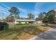 Attractive single-story home with a fenced yard, lush green lawn, and mature trees under a blue sky at 3204 Ne 16Th Ave, Ocala, FL 34479