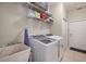 Well-lit laundry room featuring a utility sink, washer, dryer, storage shelves, and convenient access to an exterior door at 3401 Se 49Th Ave, Ocala, FL 34480