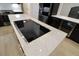 Modern kitchen island featuring cooktop, white countertop, and black cabinetry with gold hardware at 4534 Se 13Th St, Ocala, FL 34471