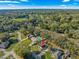 Aerial view showcases the house, pool, large green lawn, surrounding treed neighborhood and clear blue skies at 5115 Se 20Th St, Ocala, FL 34480