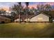 Inviting single-story home at dusk featuring a green lawn, mature trees, and tidy landscaping at 5115 Se 20Th St, Ocala, FL 34480