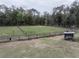 Expansive fenced backyard, showing level ground and some outbuildings on a treed lot at 5490 Se Highway 42, Summerfield, FL 34491